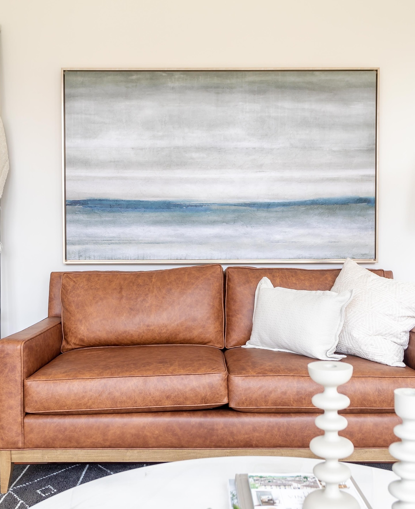 7. Hang a Wide Landscape Above a Cognac Sofa
