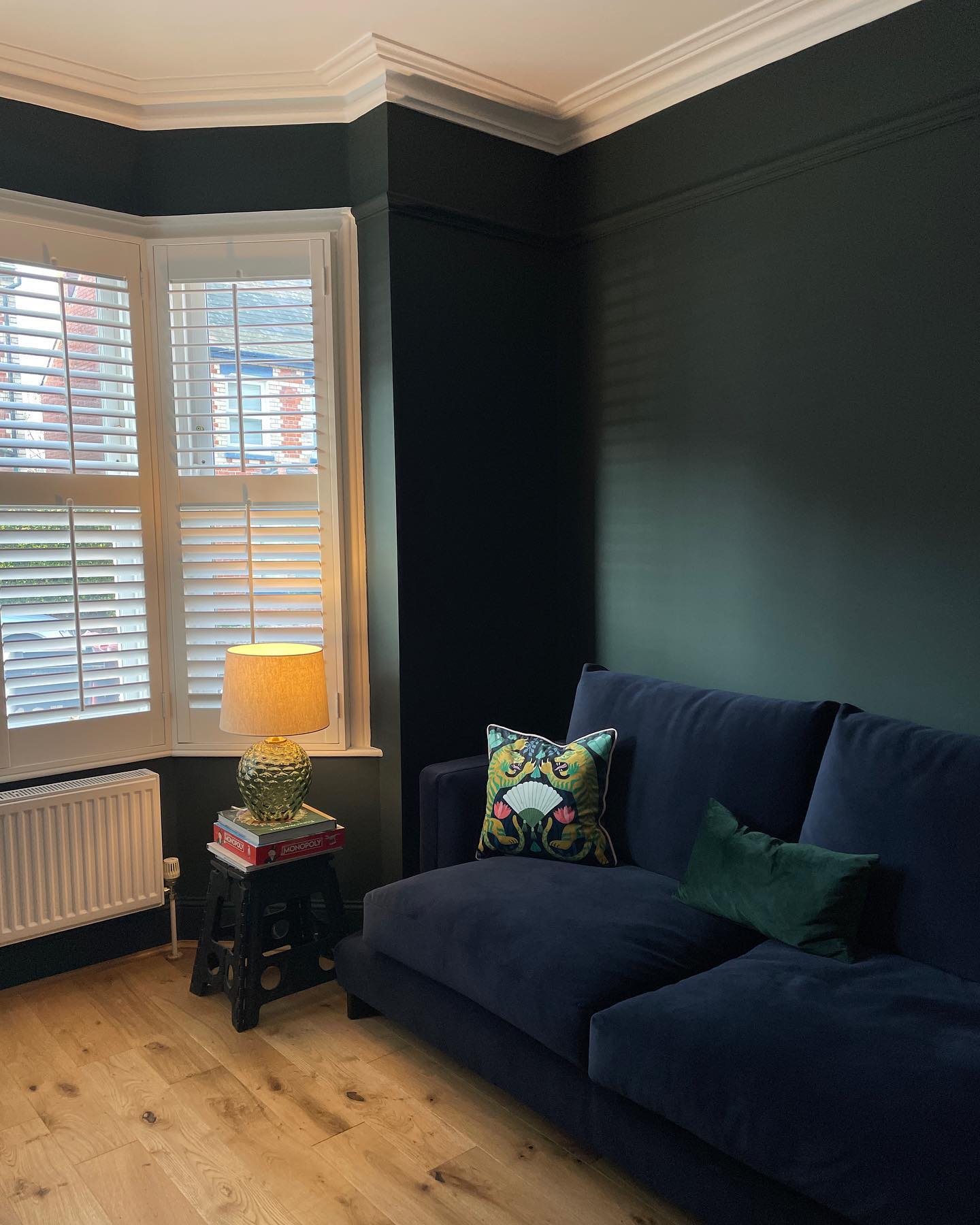 17. Deep Green Walls Behind a Navy Sofa