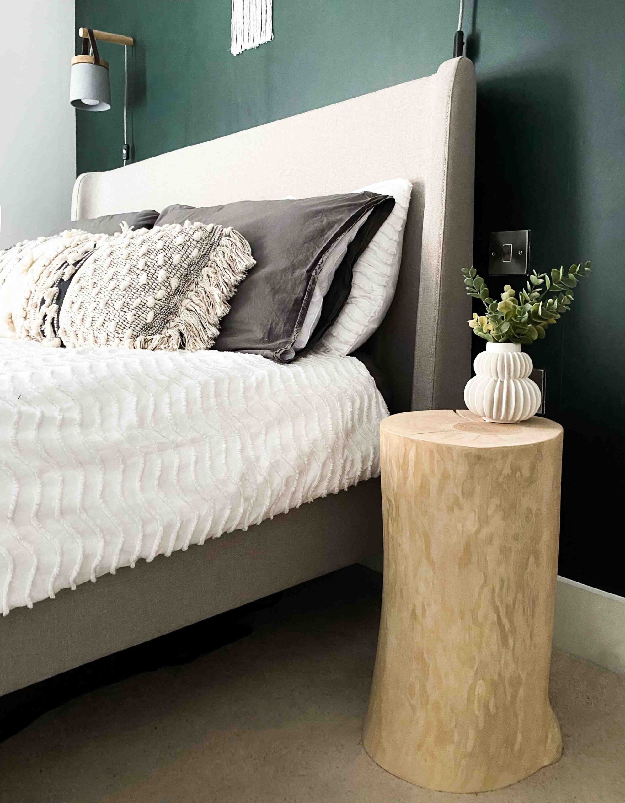 7. Bring a Sculptural Wood Stump Beside a Dark Green Bed