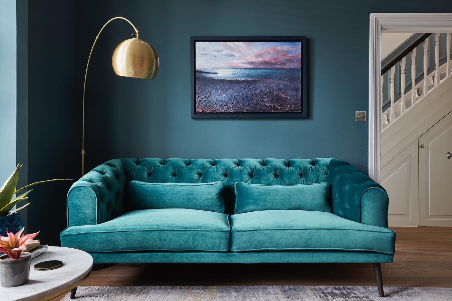 2. Pair a Tufted Teal Sofa With Darker Walls